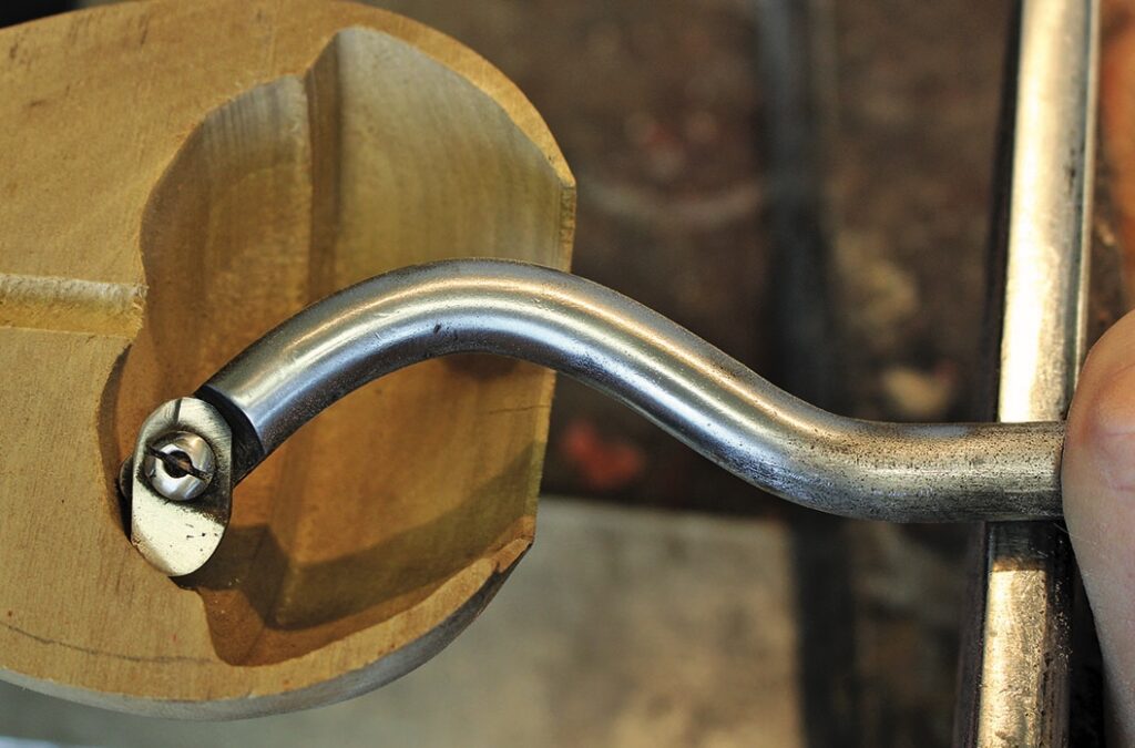 Wood carving tool and handle on wooden piece.