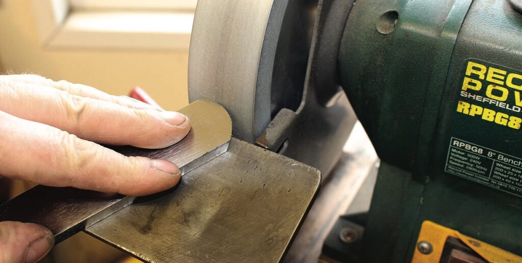 Hand sharpening metal on bench grinder