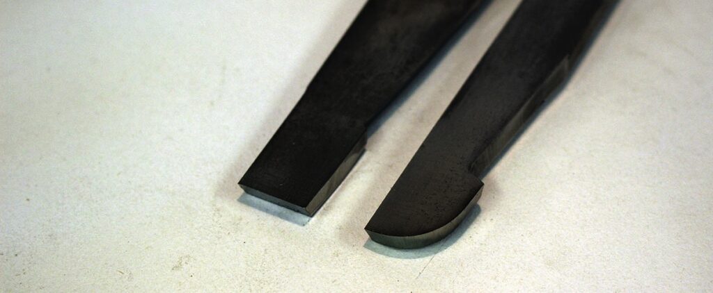 Close-up of two black chisels on white background.