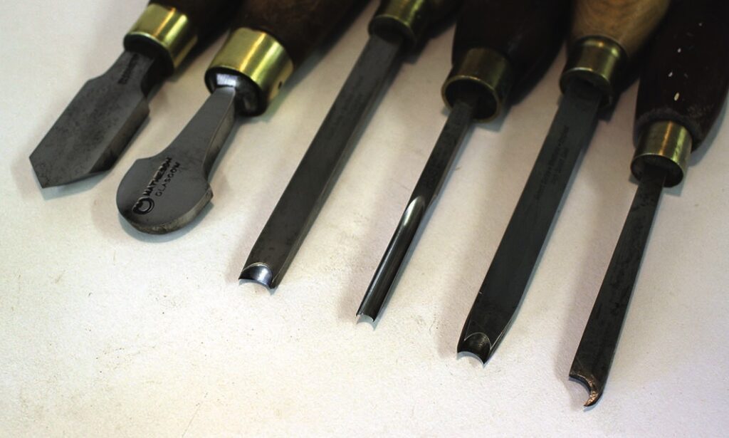 Set of various wood carving tools on table.