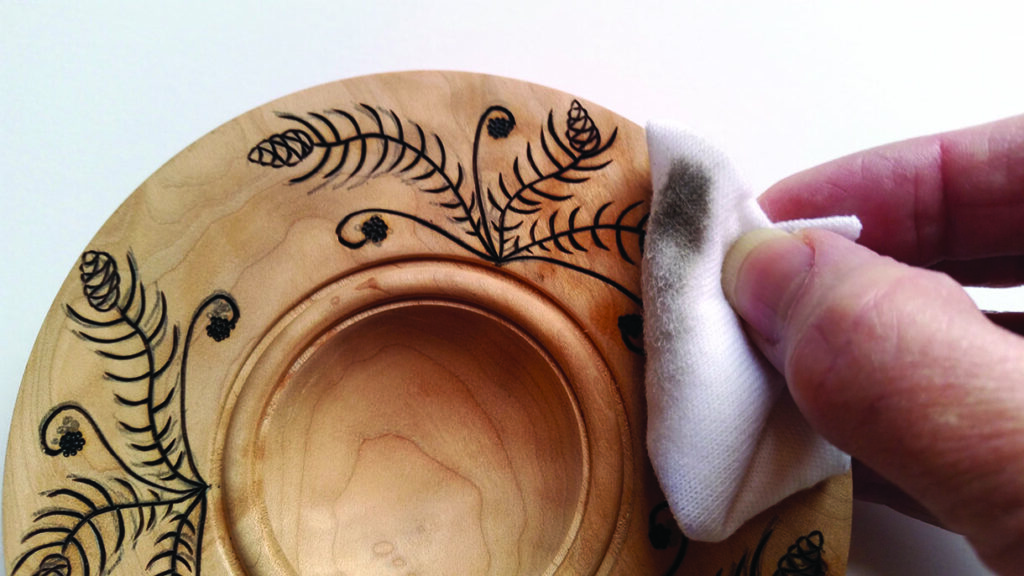 Cleaning engraved wooden plate with cloth