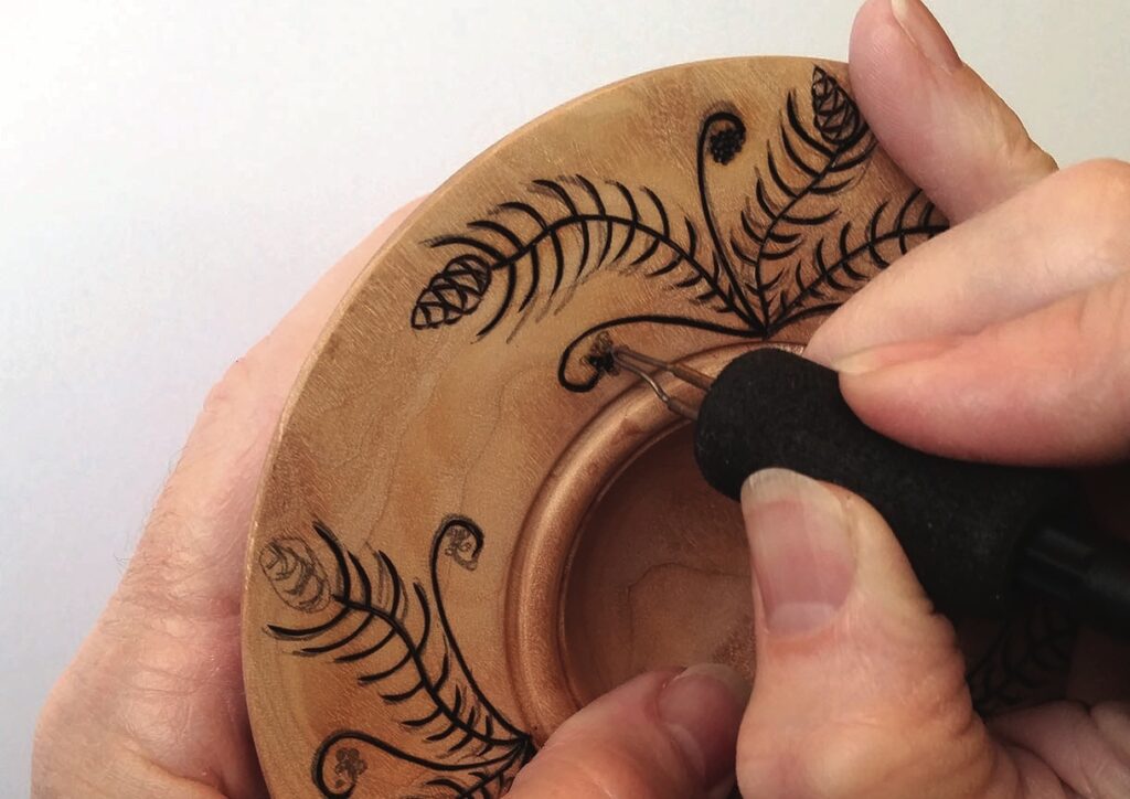 Hand engraving floral design on wooden surface.