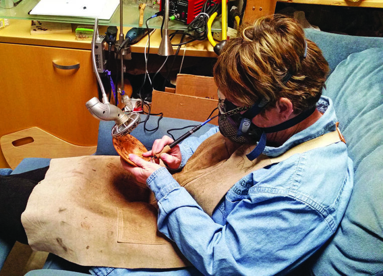 Person intricately carving wood with precision tools.