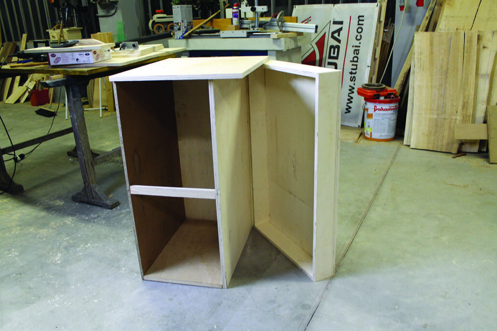 Unfinished wooden cabinet in workshop.