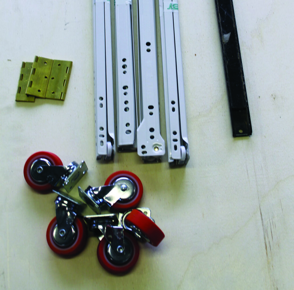 Woodwork bracket, casters, hardware on wooden surface.