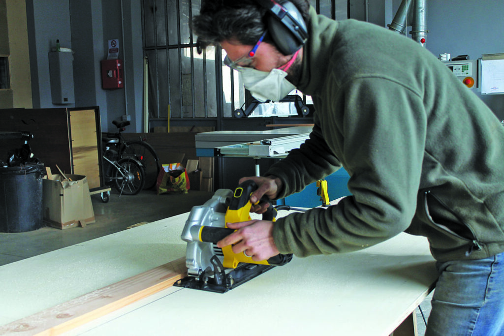 Person using circular saw on wood in workshop.