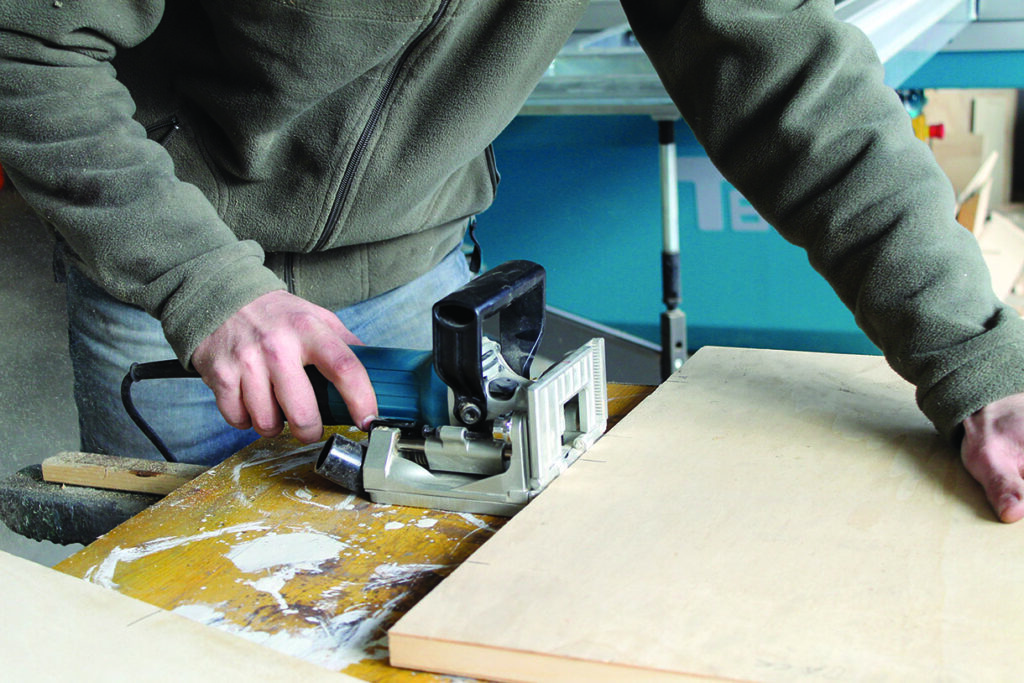 Person using woodworking tool on plywood.