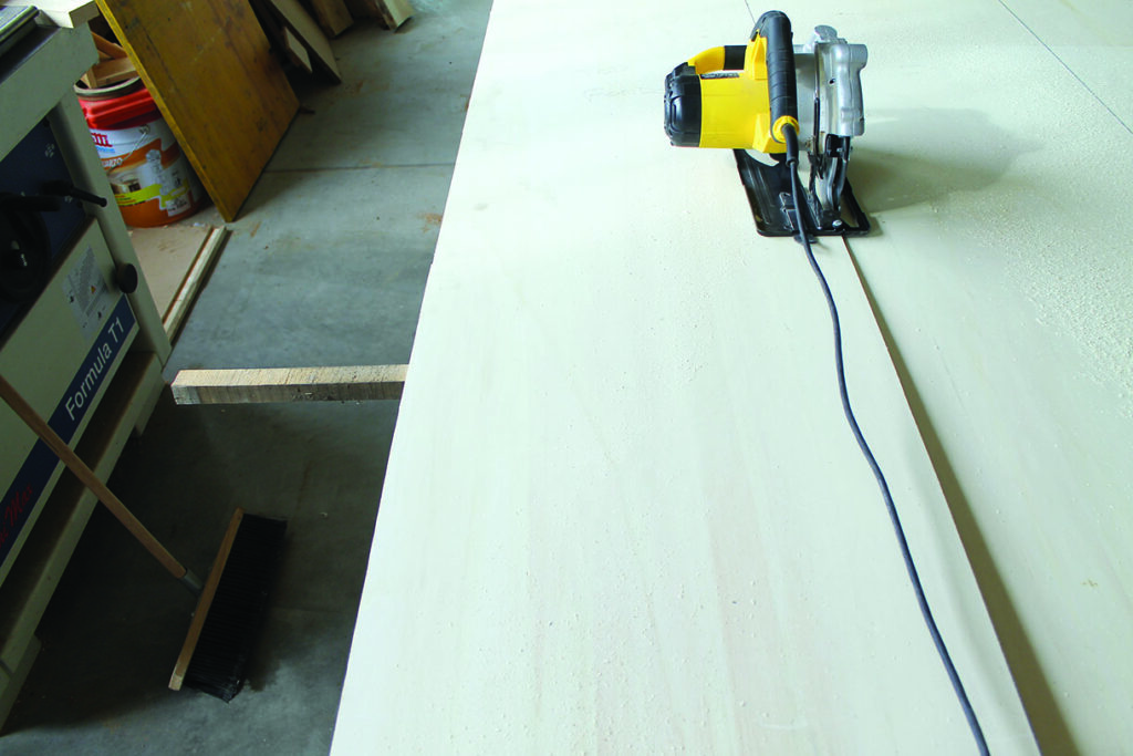 Circular saw cutting wooden board in workshop.