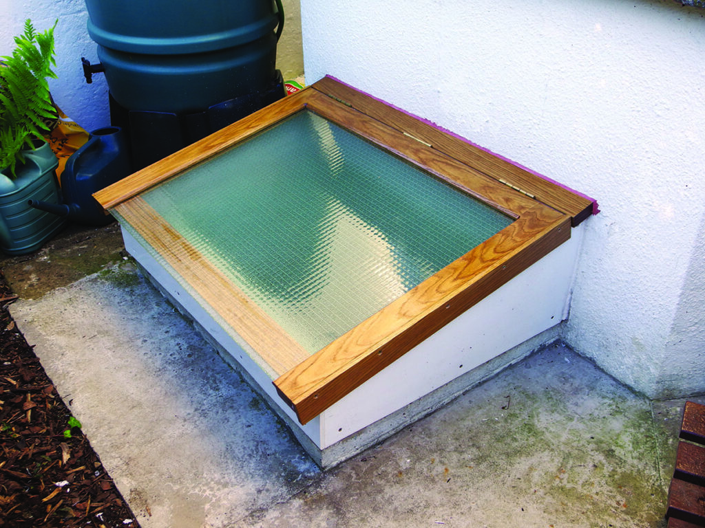 Basement window with wooden frame in garden.