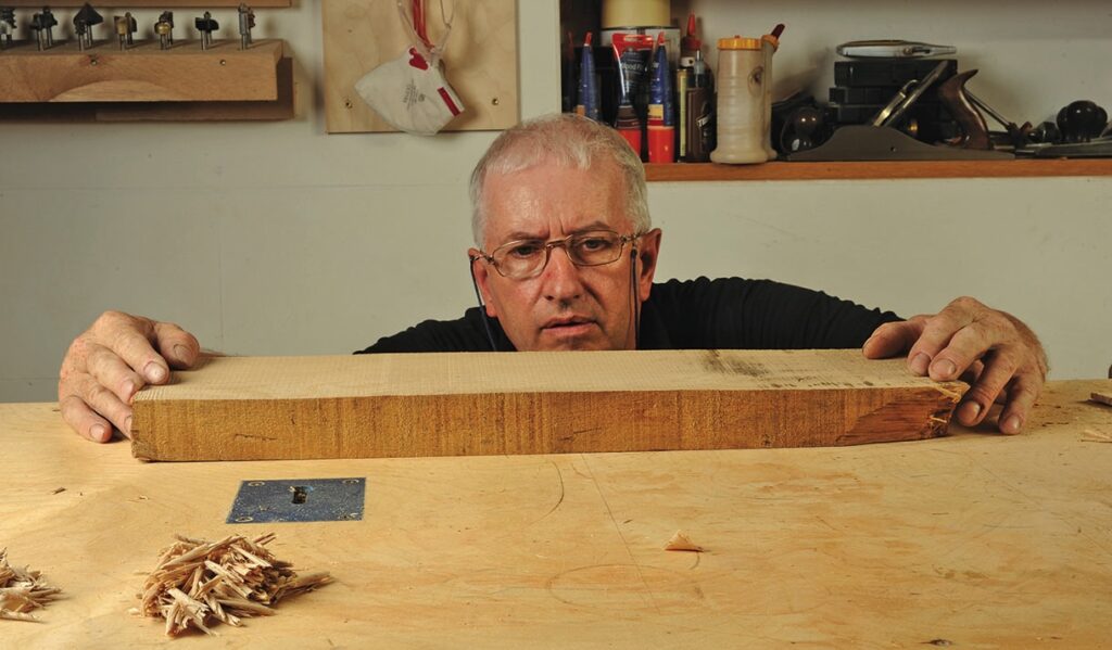 Carpenter inspecting wooden plank on workbench.