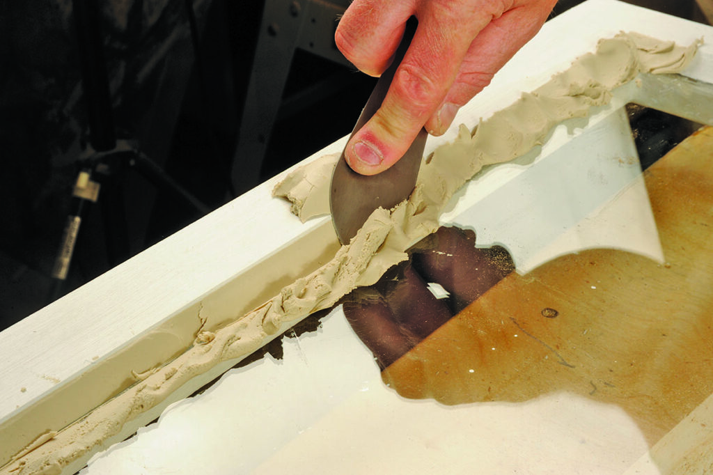 Applying putty to window frame with knife