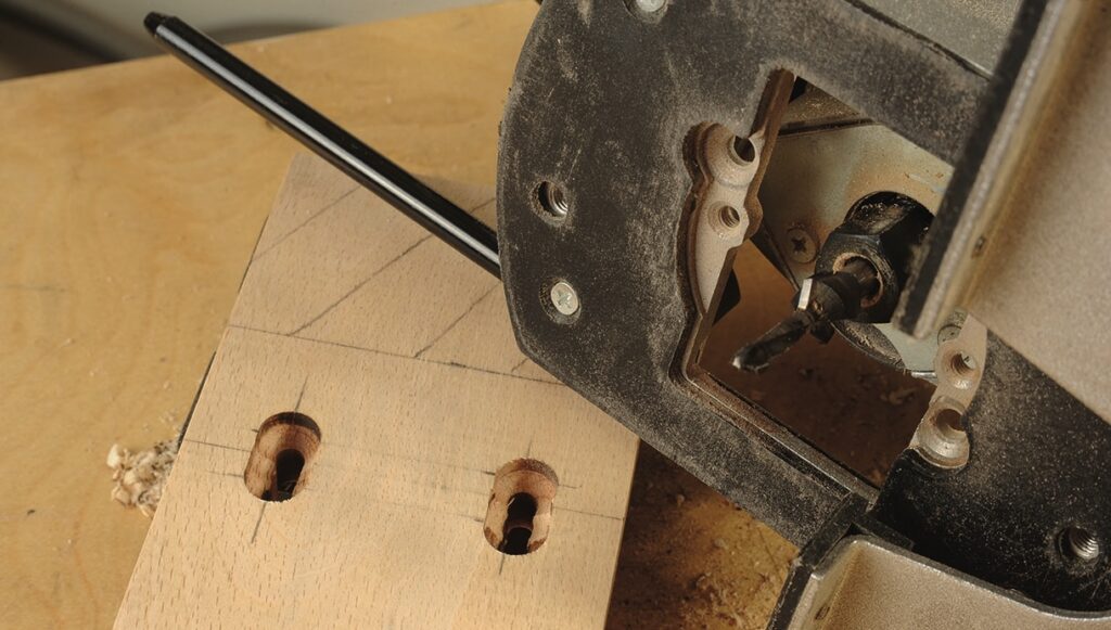 Router drilling pocket holes in wood panel.