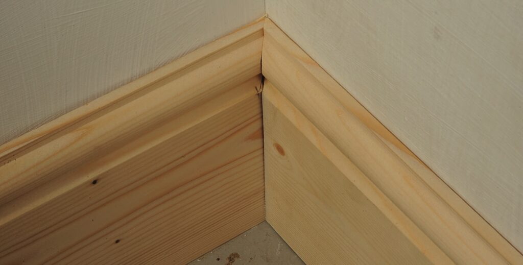 Wooden skirting board in room corner.