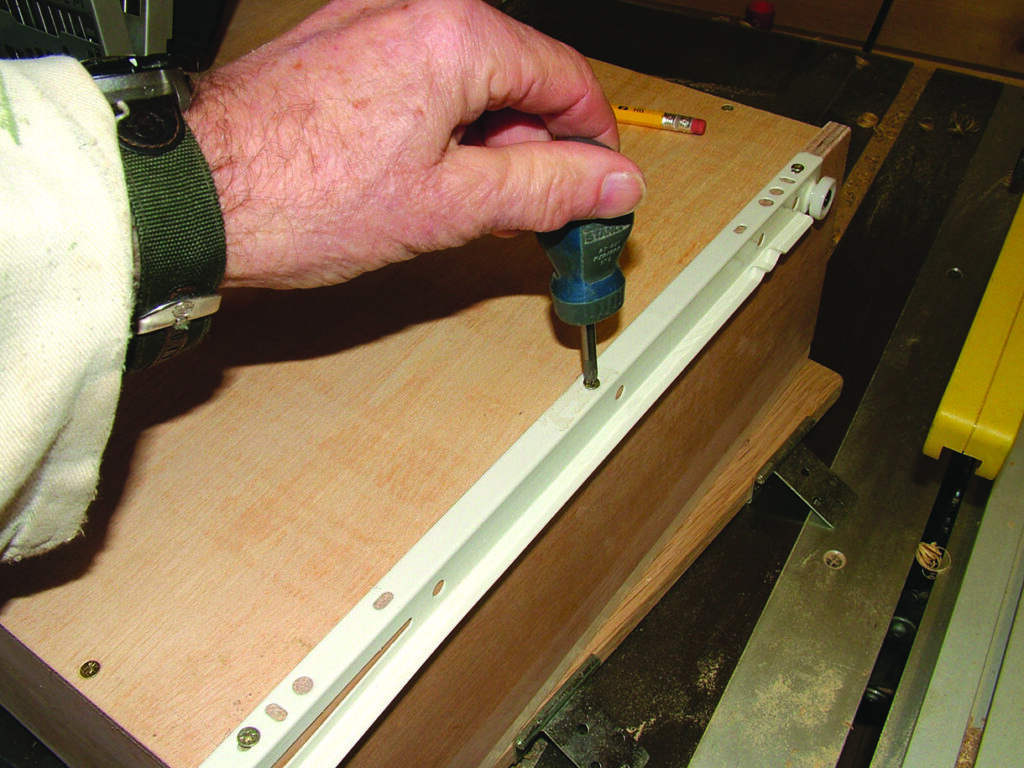 Person installing drawer rail with screwdriver.