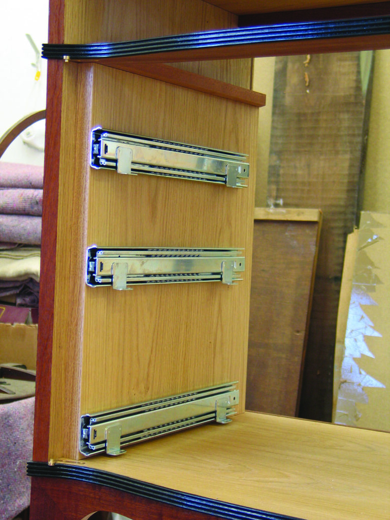 Wooden cabinet with metal drawer slides installed.
