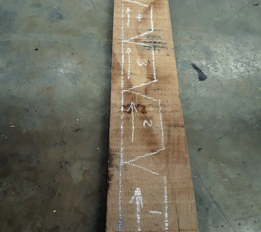 Wooden board with chalk markings on concrete floor.