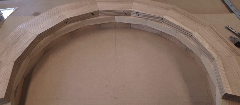 Curved wooden structure with numbered segments on table.