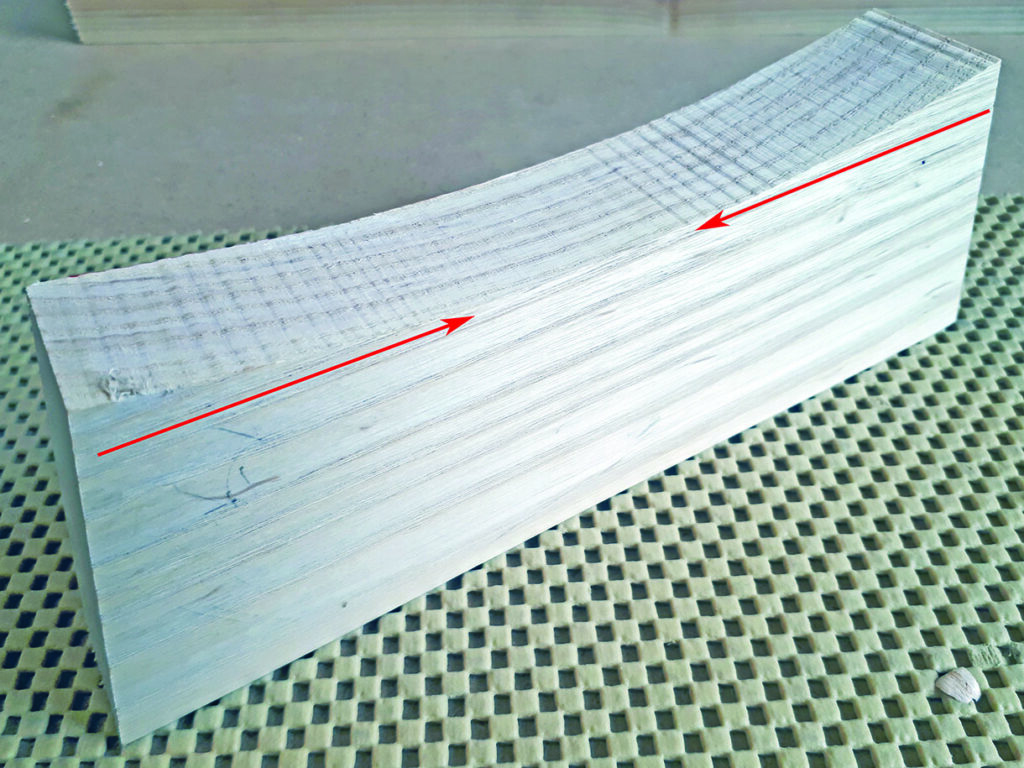 Curved wooden block with grain direction arrows.