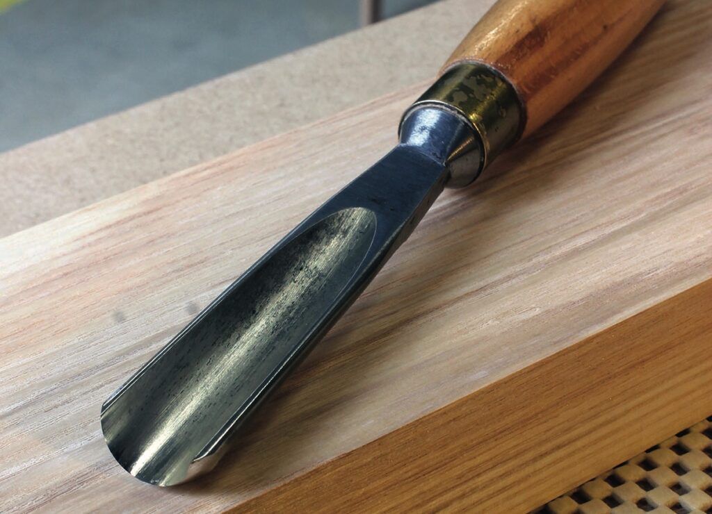 Woodcarving gouge on wooden surface.