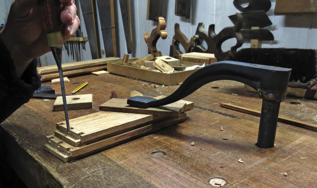 Craftsman chiselling wood joint on workbench.