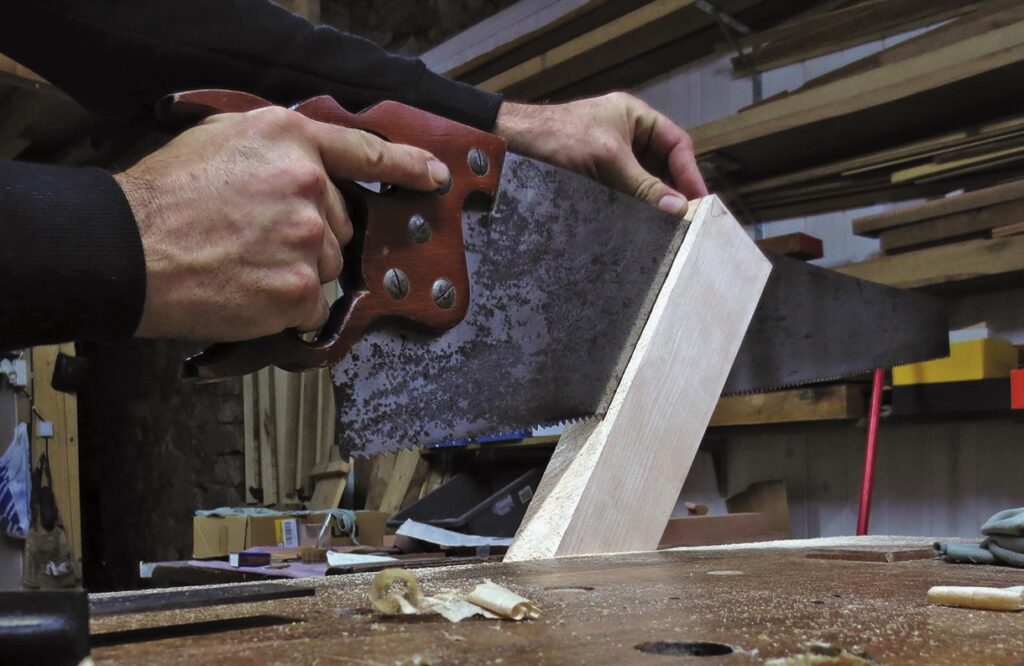 Person sawing wood in woodworking workshop.