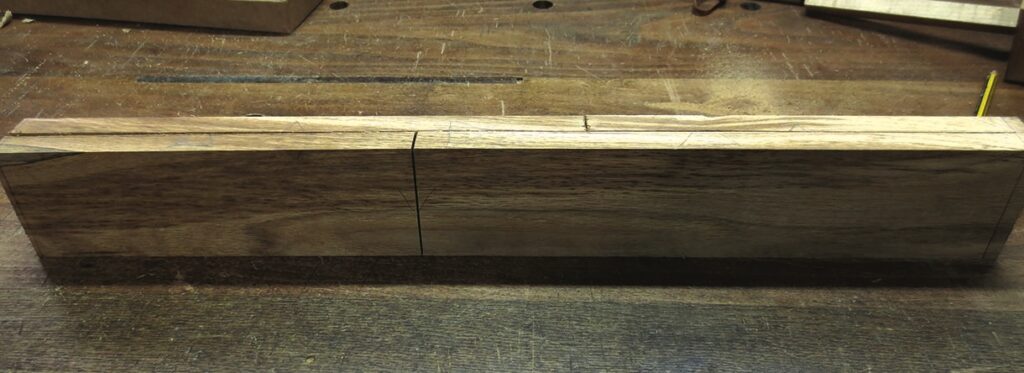 Wooden dovetail joint in progress on workbench.
