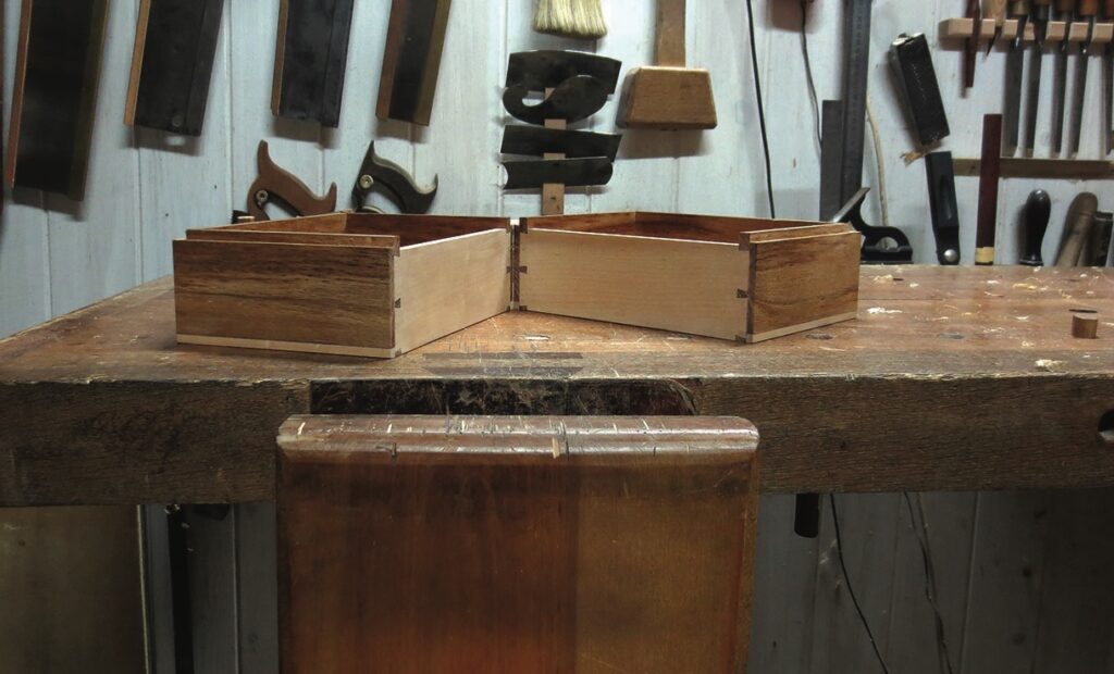 Open wooden box on workbench in carpentry shop.