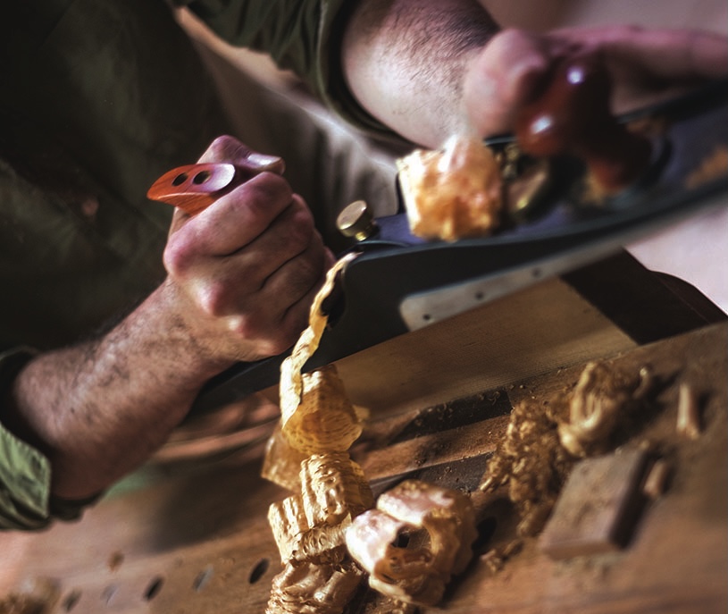 Carpenter hand-planing wood, creating curls