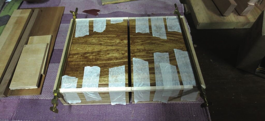 Woodwork press with tape on polished wood pieces.
