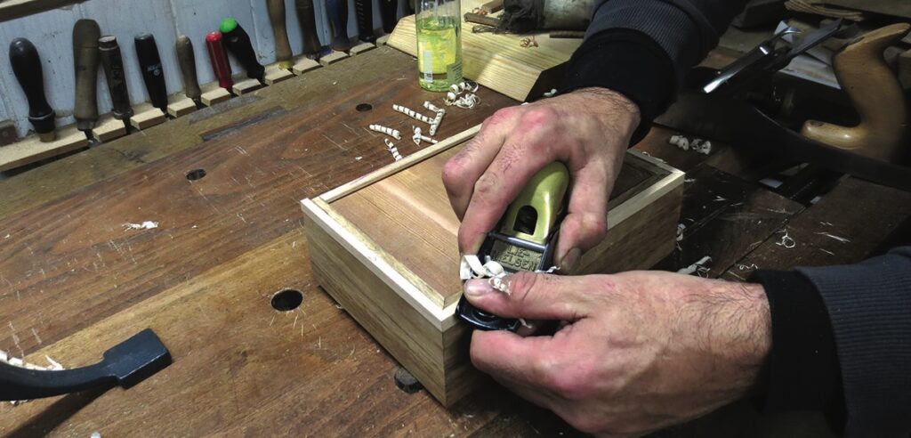 Carpenter sanding wooden box in workshop.