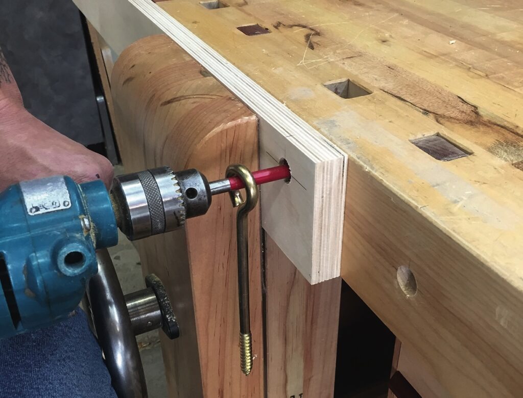 Drilling hole in wooden workbench with power drill.
