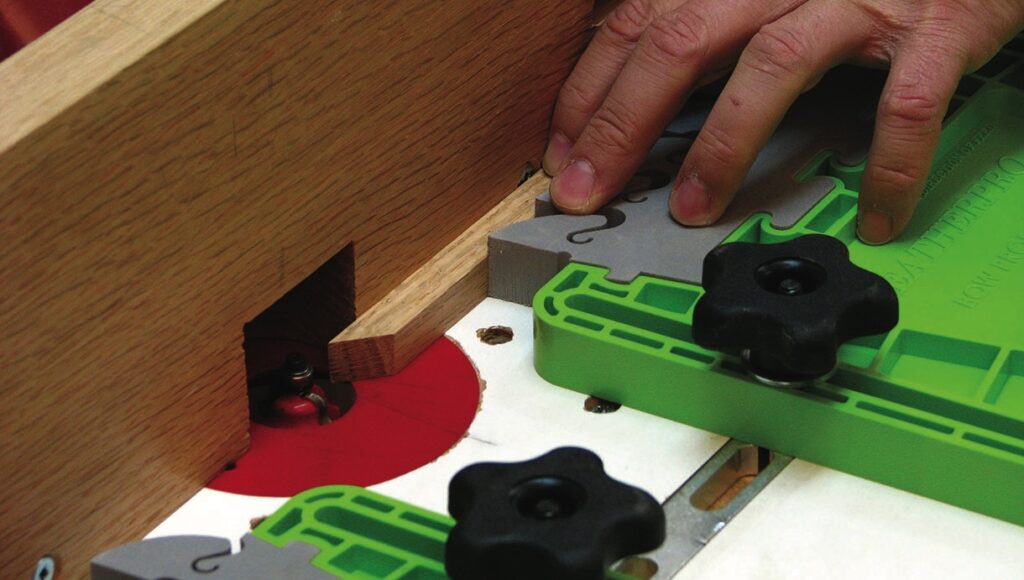 Hand using router with green template and wood