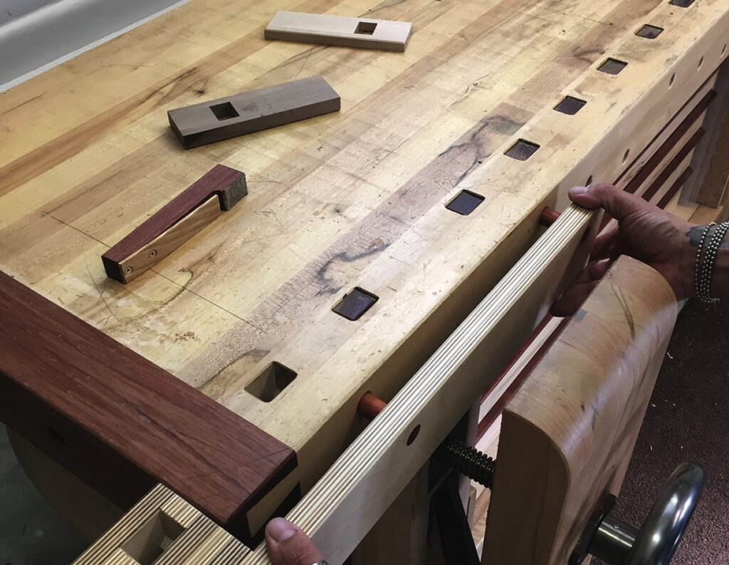 Workbench with woodworking tools, vices, and dog holes.