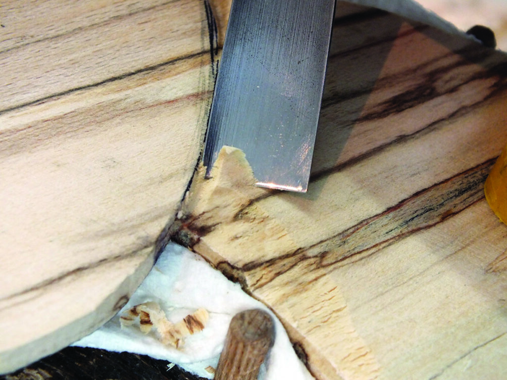 Close-up of wood chisel carving wooden surface.