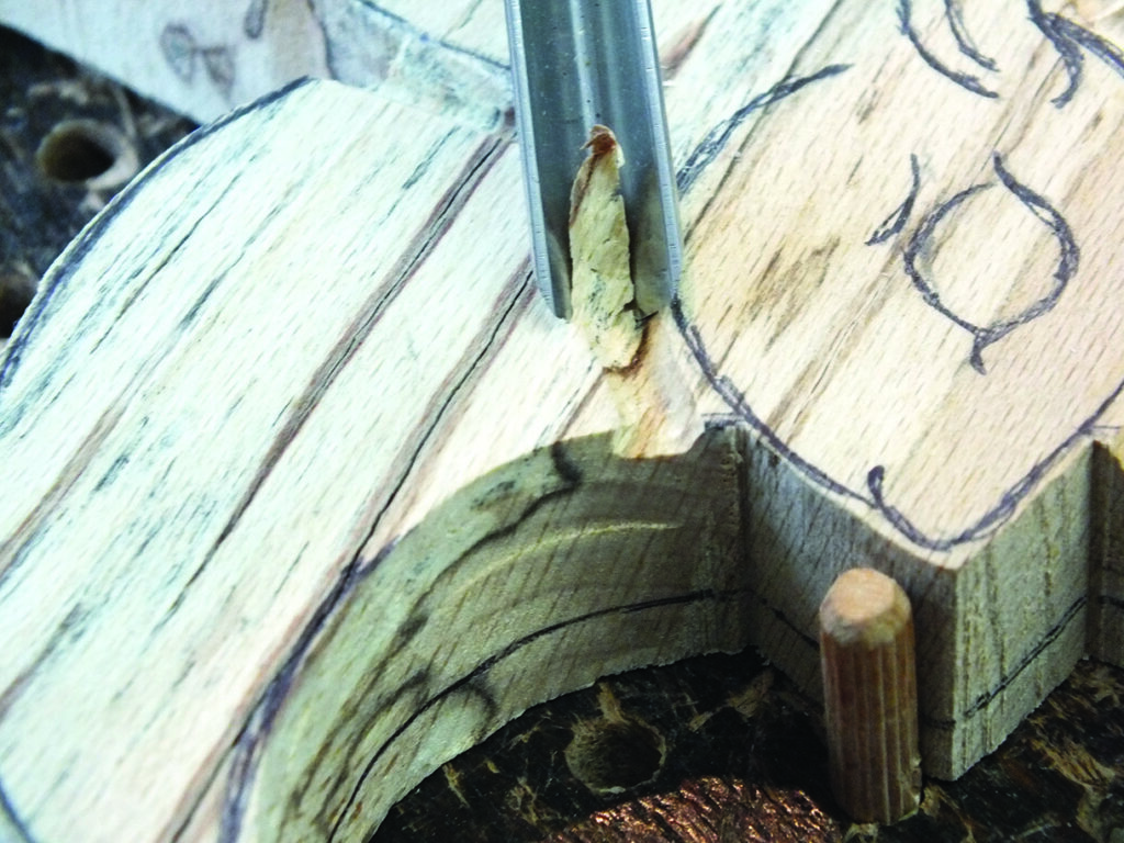 Carving wood with gouge on marked surface.
