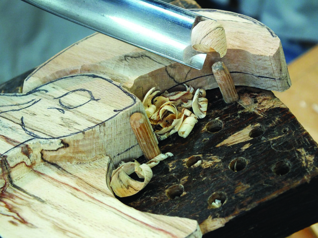 Wood carving with chisel on a wooden block.