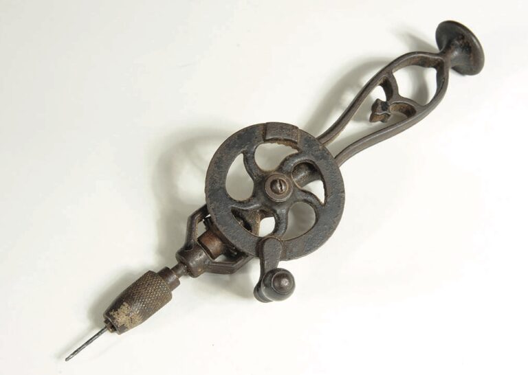 Antique hand drill with ornate handle design.
