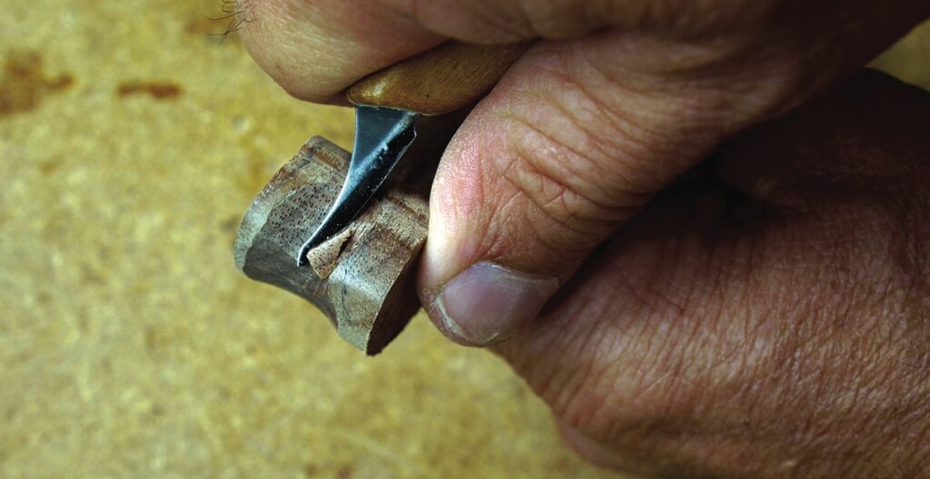 Close-up of hand carving wooden object.