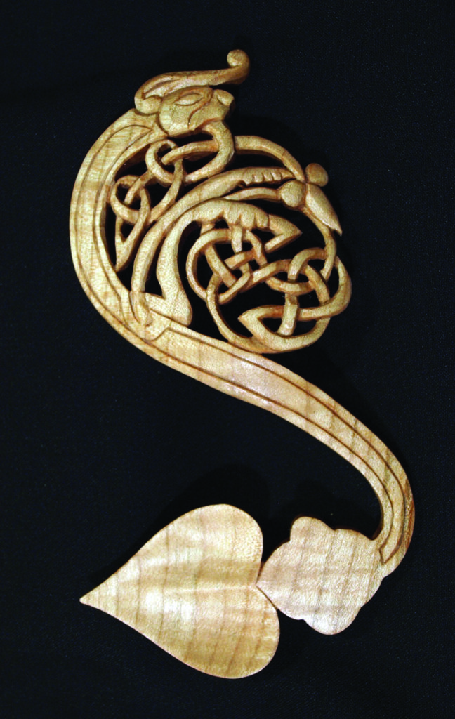 Intricate Celtic wood carving on black background.