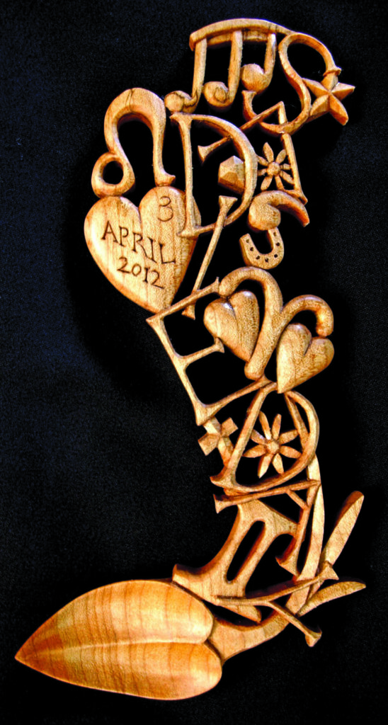 Hand-carved lovespoon with symbols and date inscribed.