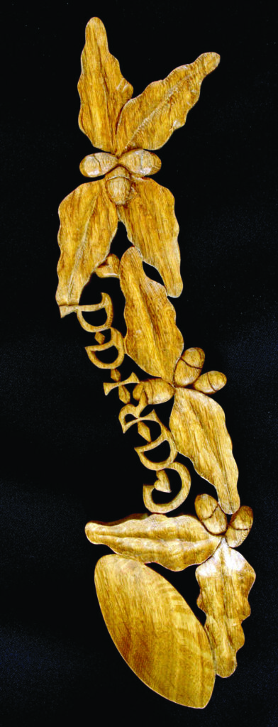 Carved wooden orchid design on black background.