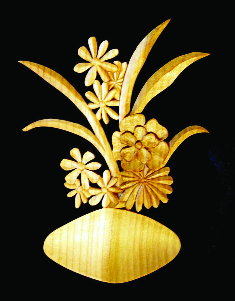 Wooden floral sculpture on black background.
