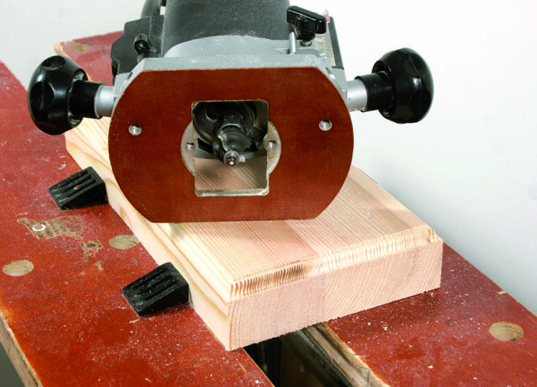 Wood router on timber plank in workshop.
