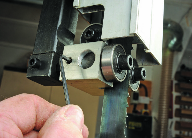 Adjusting bandsaw blade tension with hex key.