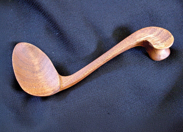Wooden kitchen spoon on black fabric background.