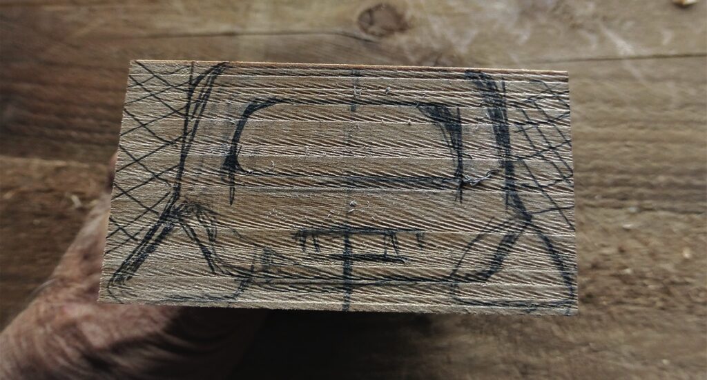 Woodblock with sketched car design on top surface.