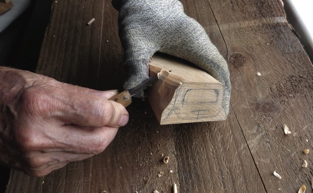 Person carving wood with hand tools