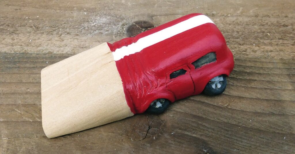 Toy car shaped like pencil on wood surface.