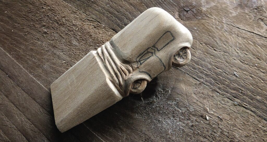 Wooden car figure carved from axe handle.