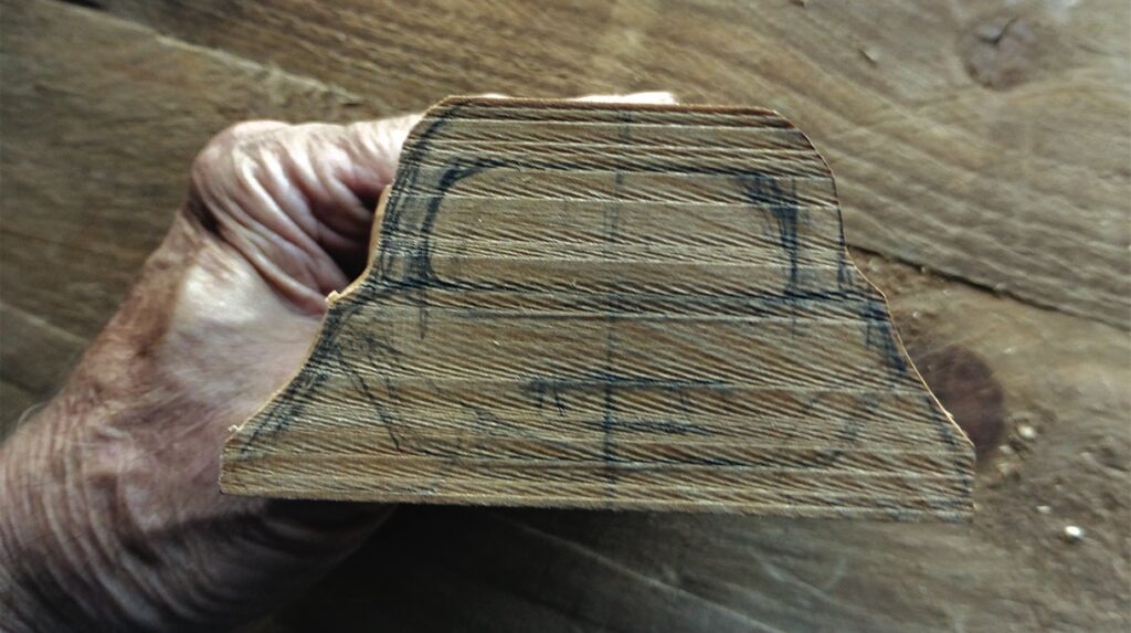 Hand holding carved wood block with markings